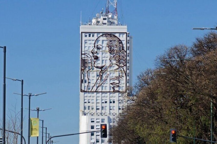 Un edificio alto con un gran mural de un rostro en su fachada. 5