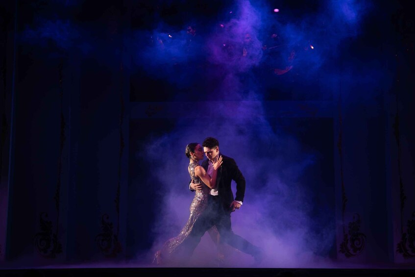 A couple dancing on a stage with smoke effects. 1
