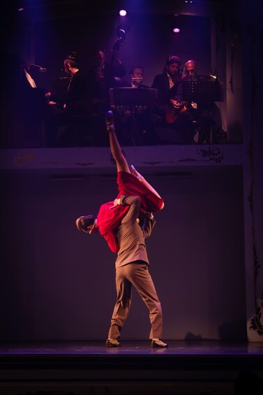 A person performing an acrobatic stunt on stage with a band in the background. 3
