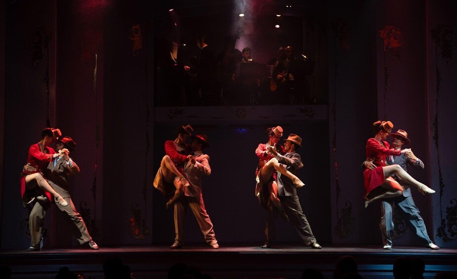 A stage with dancers in red and brown costumes performing a choreographed routine. 4