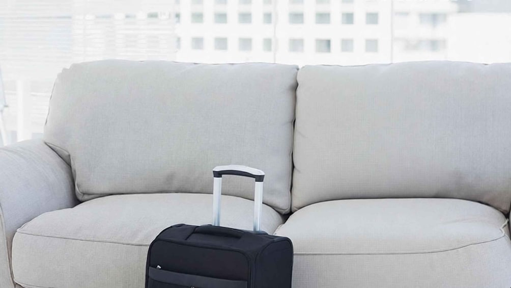 A light-colored sofa with a black suitcase in front of it. 3