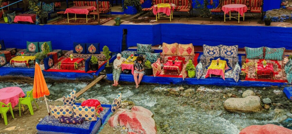 A colorful outdoor seating area with various tables and chairs, some covered with umbrellas. 5