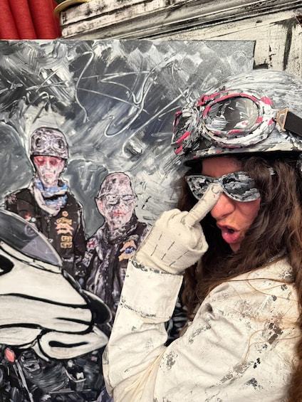 A person wearing a helmet with a reflective visor, a scarf, and a jacket with paint splatters. 3