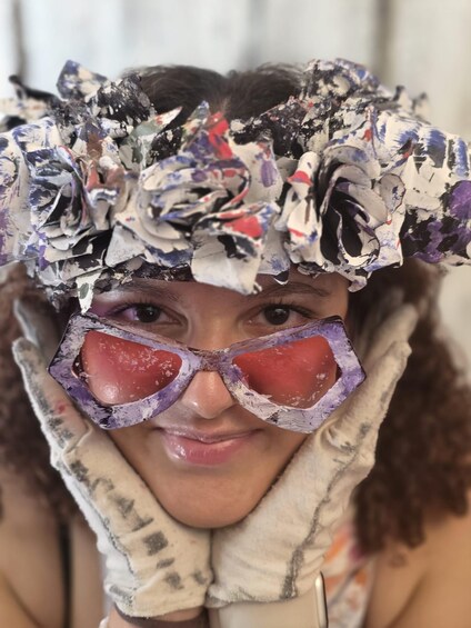 A person with a headpiece made of crumpled paper and a face mask. 1