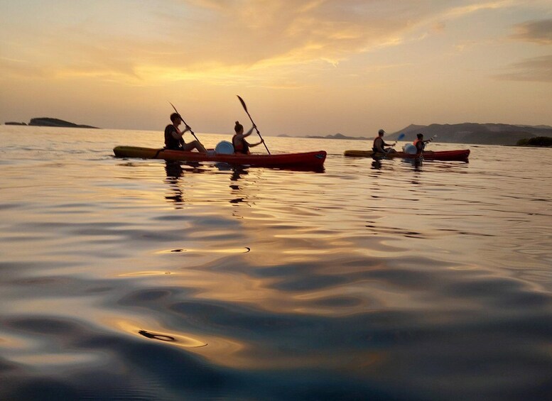 Three canoes on calm water with a sunset in the background. 3