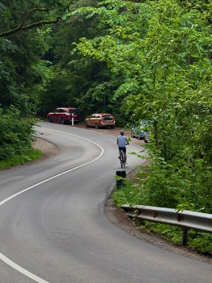 A winding road with a cyclist and parked cars. 4