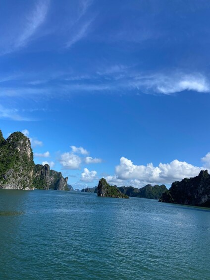 A calm sea with rocky islands and cliffs under a clear blue sky. 1
