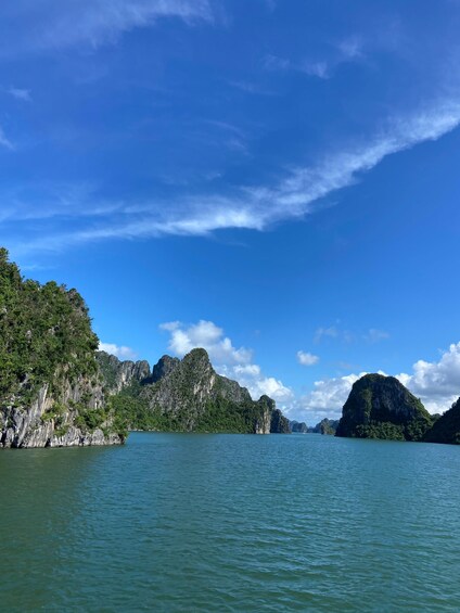A calm sea with greenish water, surrounded by lush green cliffs and clear blue sky. 4