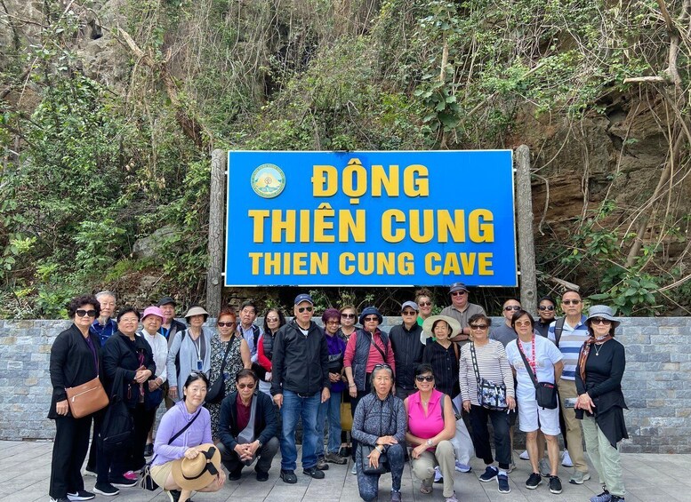 A group of people posing in front of a sign for Thien Cung Cave. 5