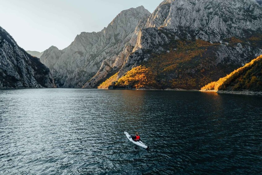A kayaker on a calm lake surrounded by rocky mountains. 4