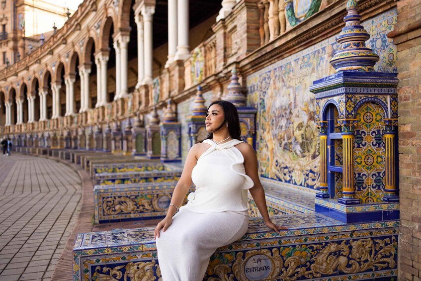A woman sitting on a tiled bench in a historic plaza with ornate columns and patterned walls. 1
