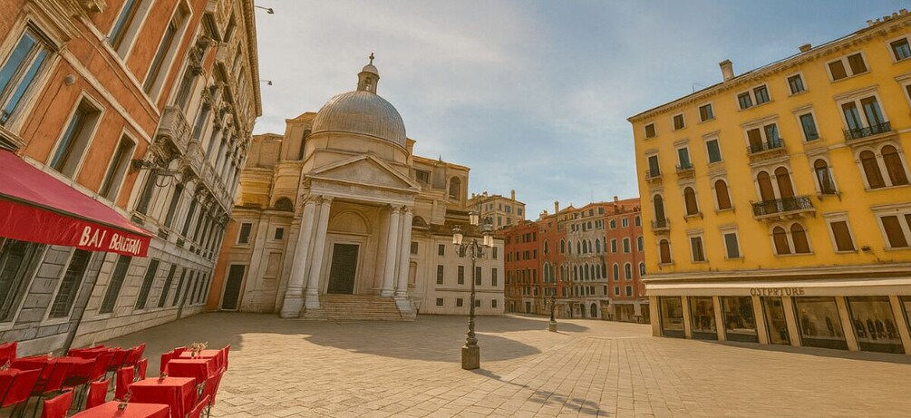 A historic square with a prominent church featuring a dome, red chairs, and classic European architecture. 2