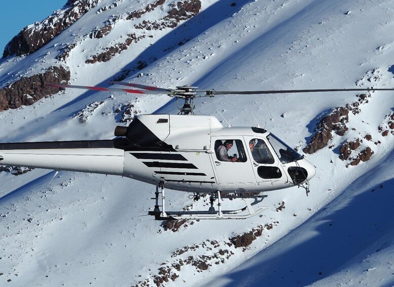 A helicopter flying over a snowy mountain. 5