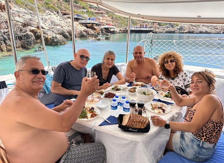 A group of people dining on a boat with a rocky coastline in the background. 5