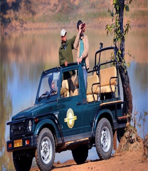 A dark green off-road vehicle with a logo on the side parked by a lake. 5