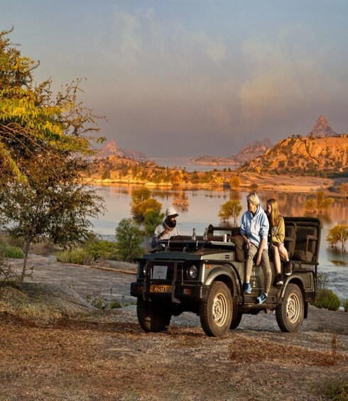 A jeep parked by a lake with a rocky landscape and trees in the background. 4