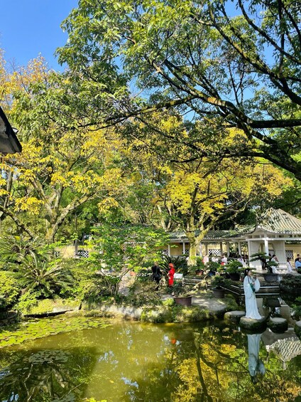 A serene garden with a pond, lush trees, and traditional architecture. 4