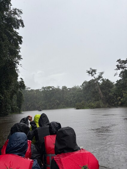 People in life jackets on a boat in a forested area. 4