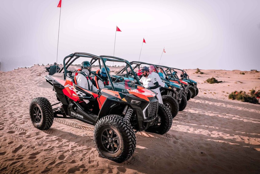 A row of ATVs parked on a sandy beach with flags in the background. 3