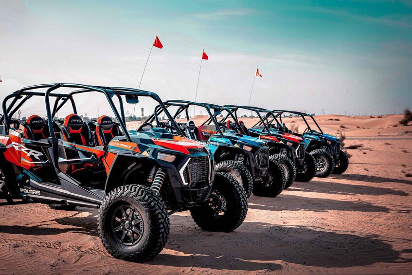 A row of off-road vehicles parked on a sandy terrain with flags. 4