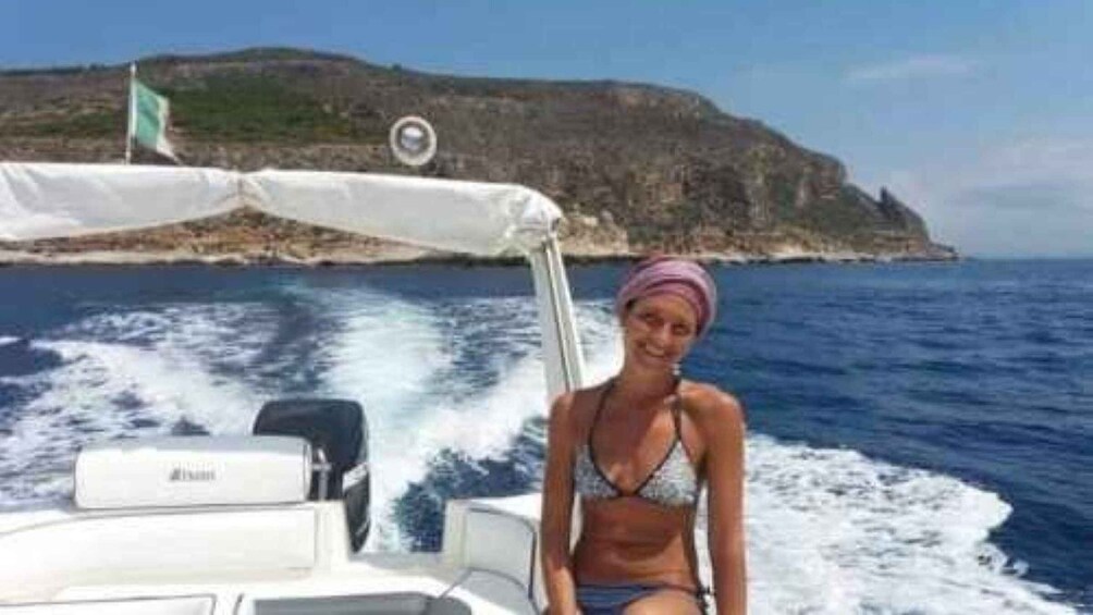A person on a boat with a rocky coastline in the background. 3