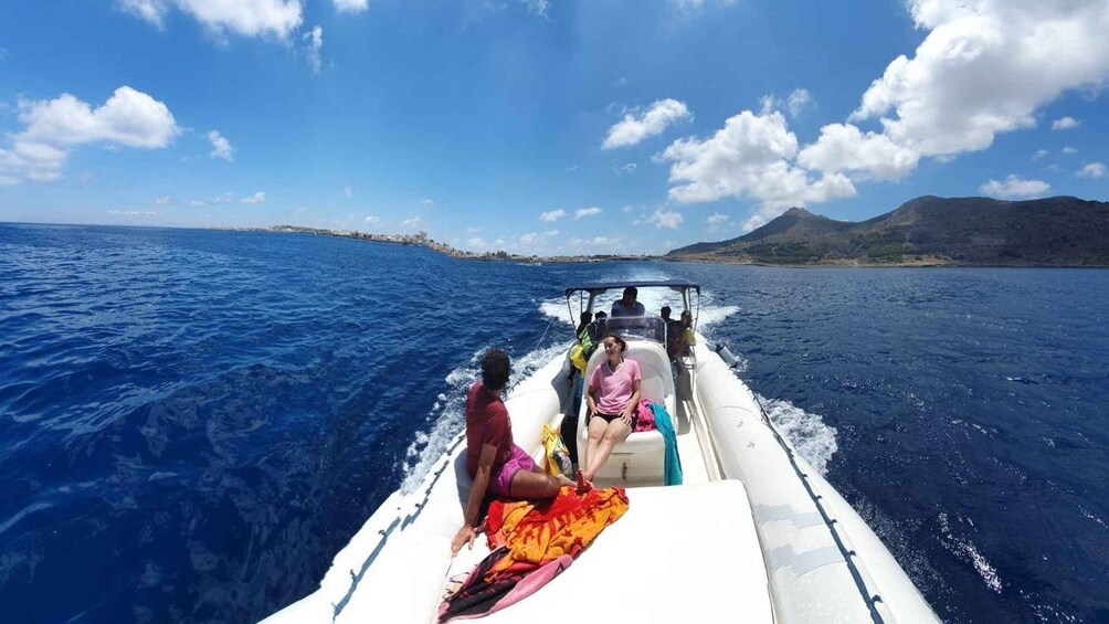 A boat on the ocean with people on board and a coastline in the background. 1