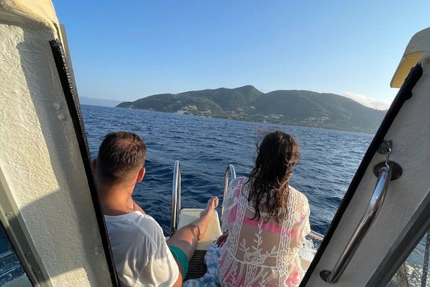 Two people on a boat with a view of the sea and distant hills. 4