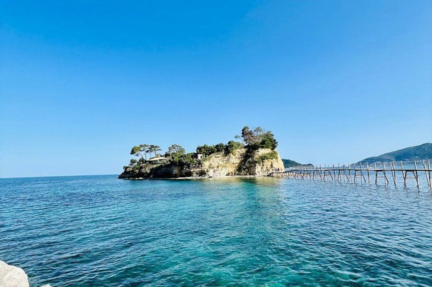 A coastal scene with a small island, clear blue water, and a wooden pier extending into the sea. 3