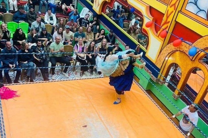 A person performing an acrobatic act with a large prop on a colorful stage. 3
