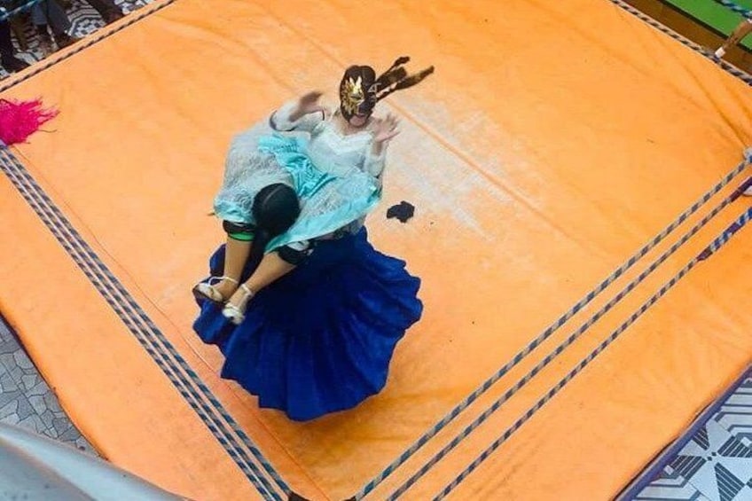 A person in a blue skirt and white top performing on an orange mat. 4