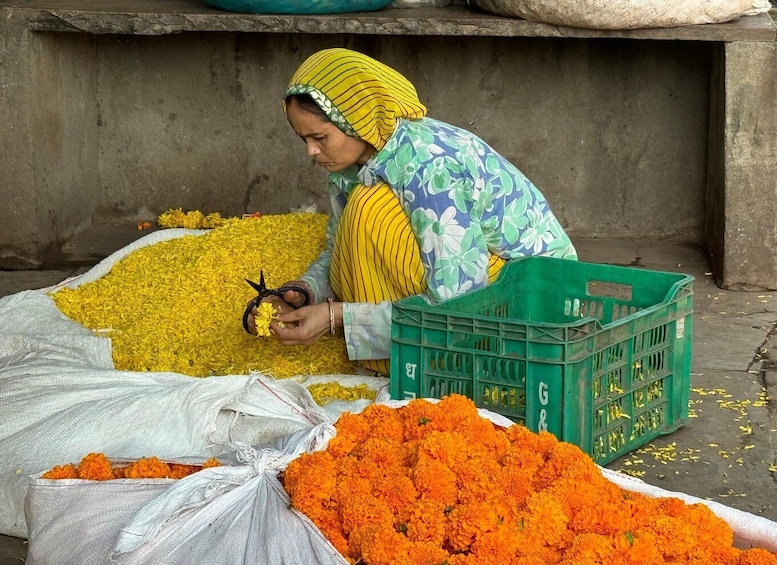 A person sorting yellow and orange flowers, likely marigolds, in a market setting. 1