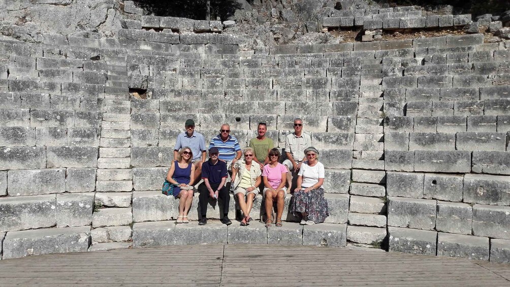 A group of people posing in front of an ancient stone wall. 2