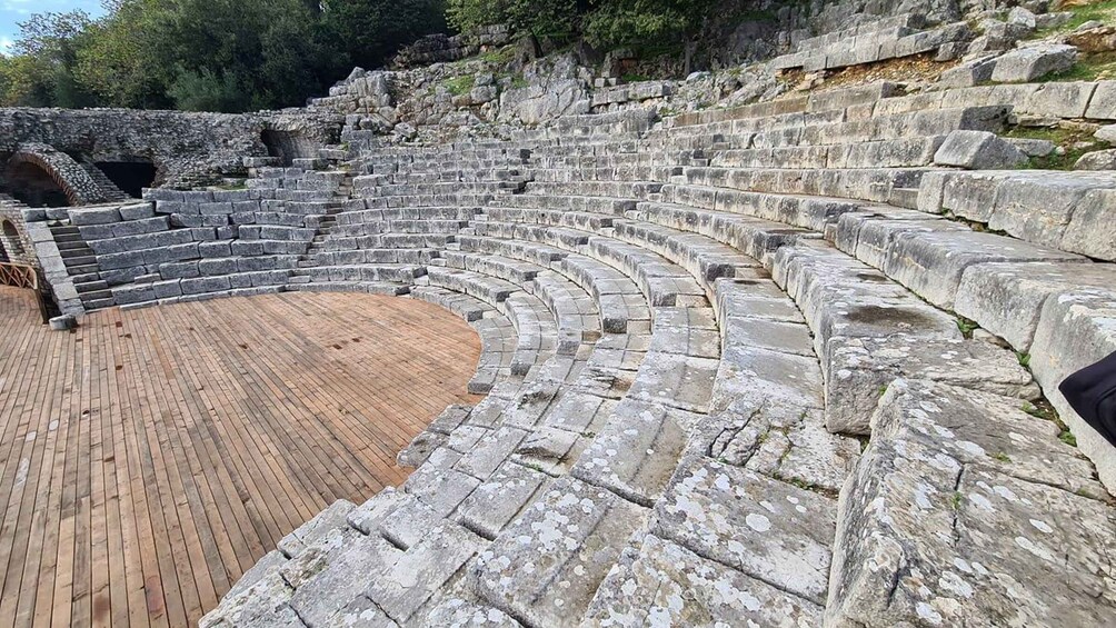 An ancient amphitheater with stone seating and a wooden stage. 4