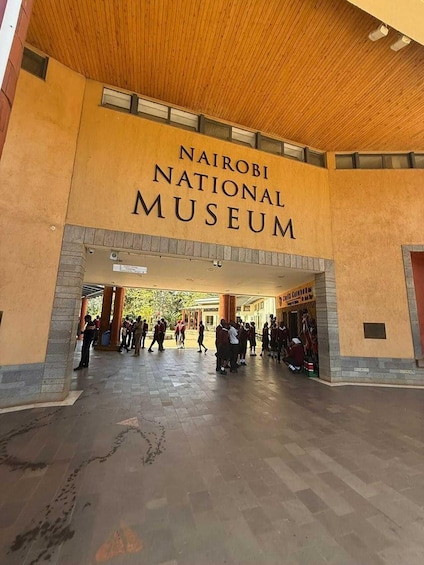 Nairobin kansallismuseon sisäänkäynti, jossa on puinen katto ja ihmisiä kävelemässä ympäriinsä. 1
