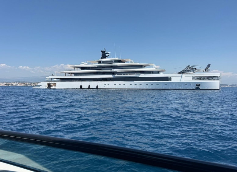 A large, multi-deck yacht with a helicopter on deck, sailing on a calm sea. 5