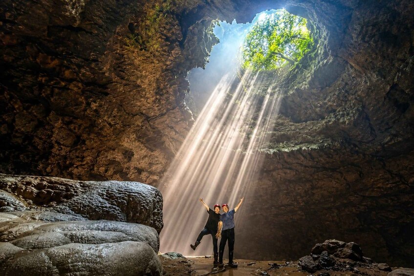 A cave with a large opening at the top, allowing sunlight to shine through. 1