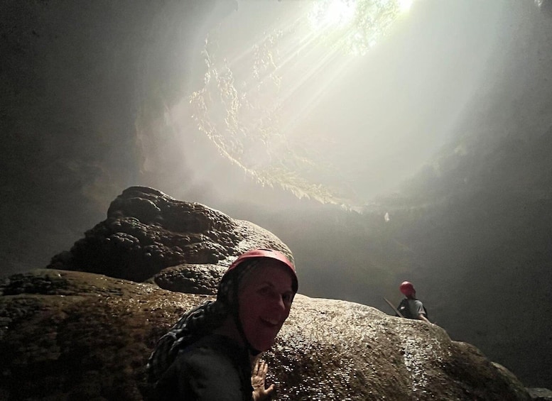 A person in a red hat sitting on a rock with a cave opening in the background. 5