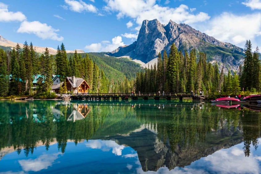 A mountain lake with reflections, a wooden cabin, and a bridge. 1