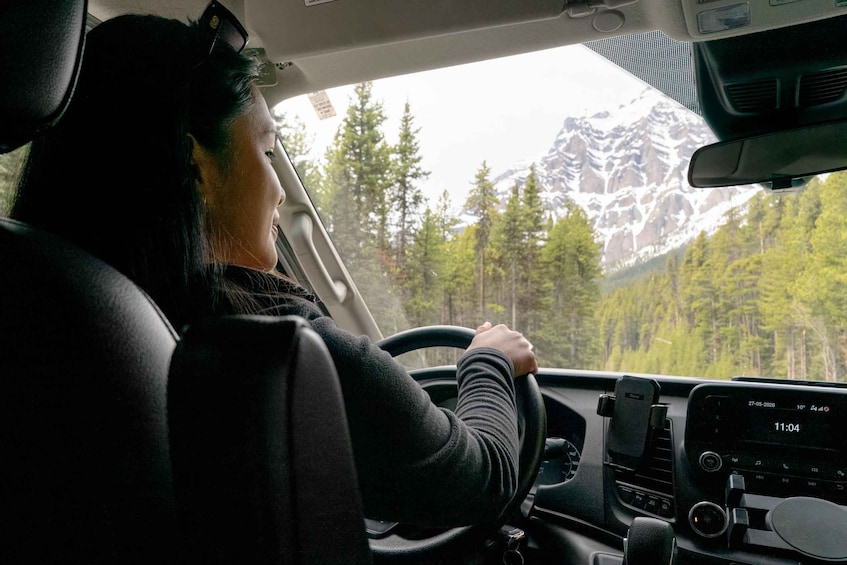 A person driving a car with a mountainous landscape visible through the windshield. 4