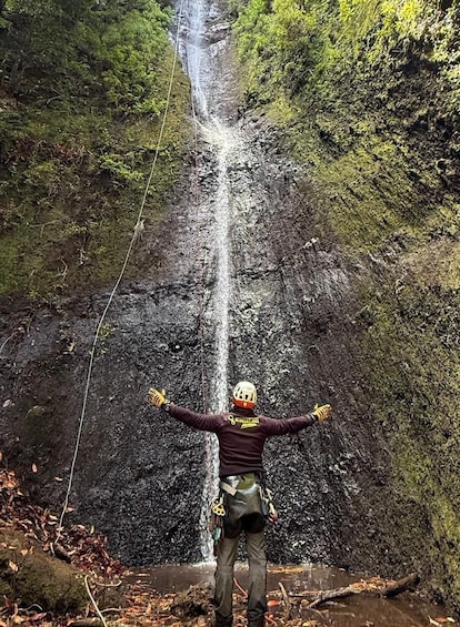 A person standing in front of a waterfall with arms outstretched. 2