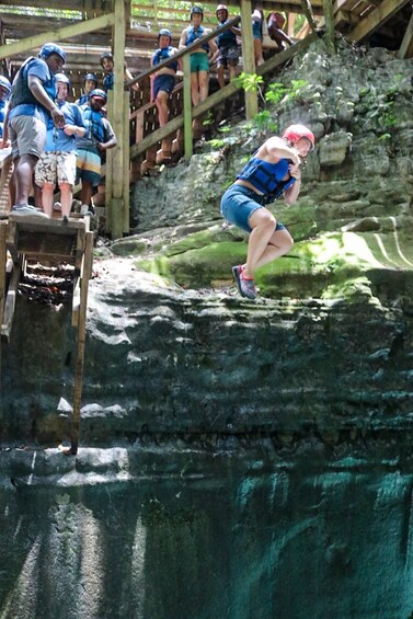 A person in a blue life jacket jumping off a wooden platform. 3