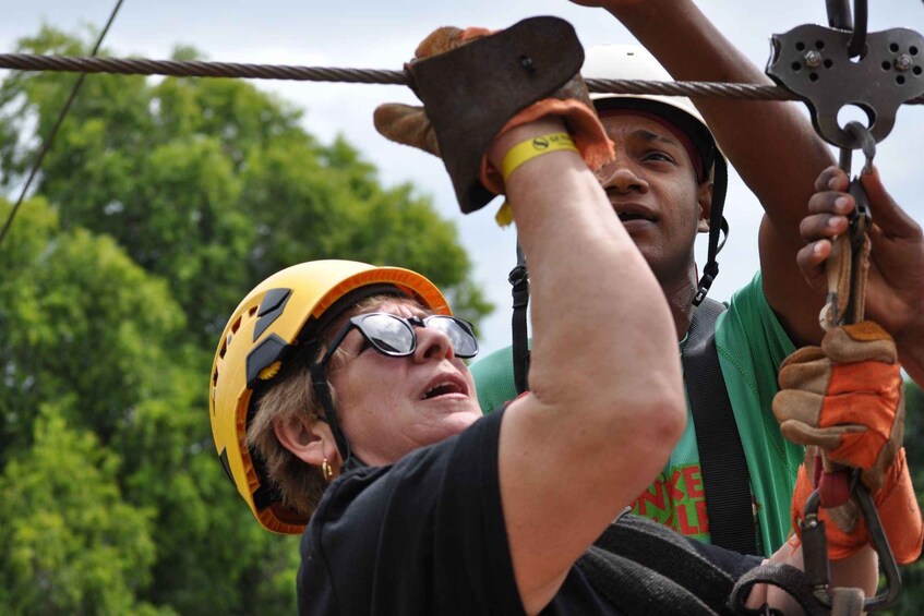 Two people wearing helmets and harnesses, engaged in a zip-lining activity. 5