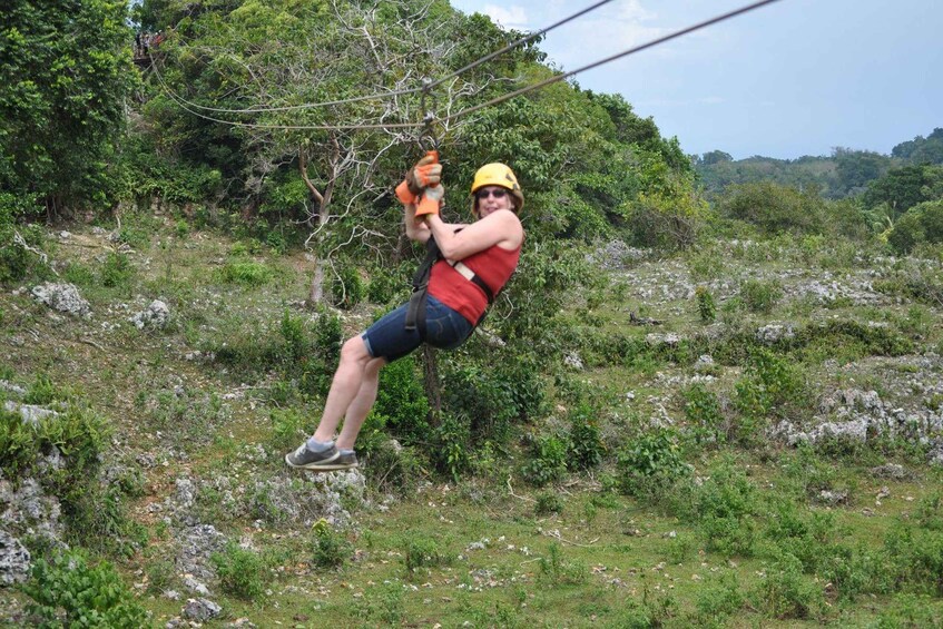A person zip-lining through a forested area with dense greenery and rocky terrain. 2