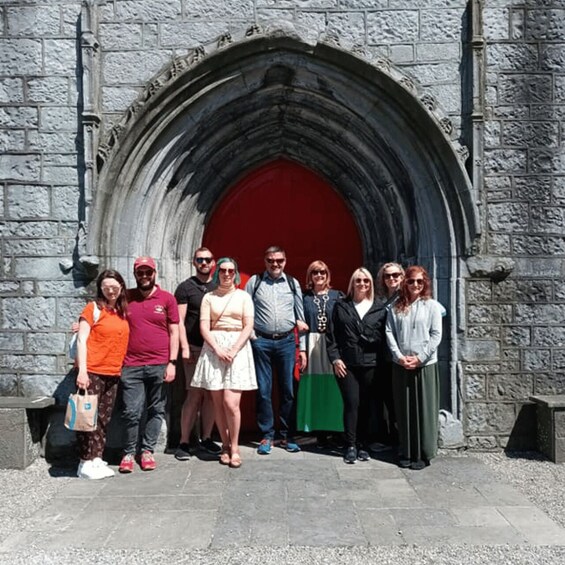 A group of people standing in front of a stone archway with a red door. 3