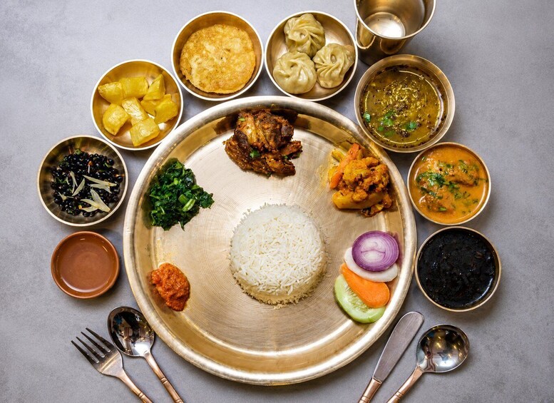 A variety of Indian dishes including rice, curries, and vegetables on a metal plate. 1