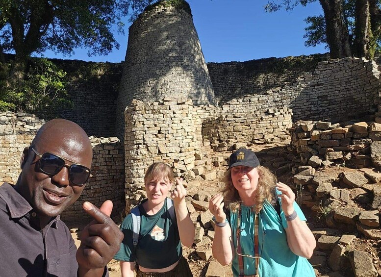 A group of people standing in front of ancient stone ruins. 1