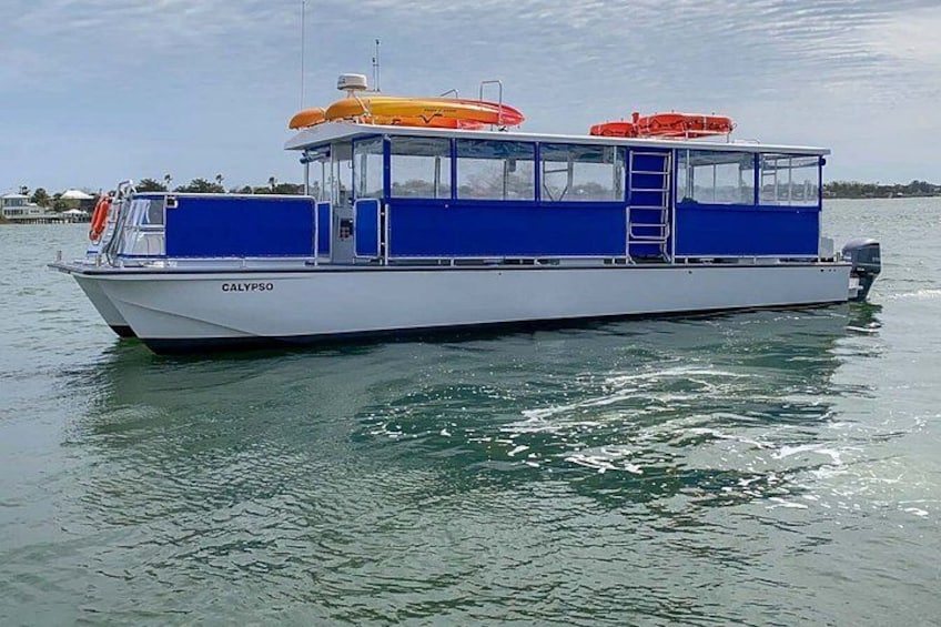 A white and blue boat named CALYPSO on calm water. 3