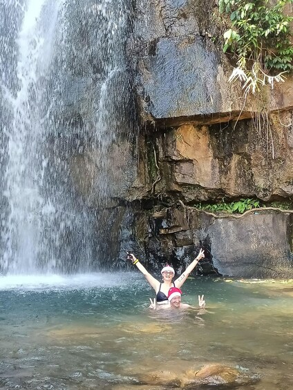 A person in a swimsuit with arms raised in front of a waterfall. 5