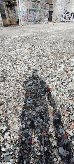 A ground covered with small stones and pebbles, with graffiti on a wall in the background. 2