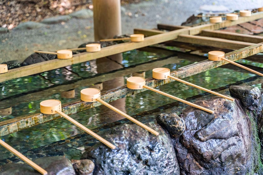 Eine traditionelle Holzbrücke über einen steinernen Kanal, auf dessen Pfählen Holzbecher balancieren. 5